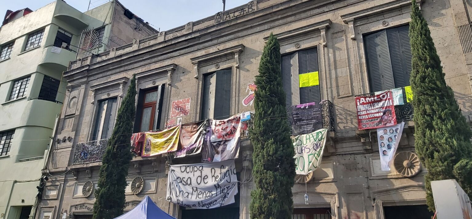 Feministische Besetzung der Nationalen Menschenrechtsbehörde in Mexiko-Stadt. Am Haus hängen Transparente mit politischen Forderungen