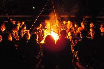 Das Bild zeigt ein Lagerfeuer mit Menschen, die für die Basisorganisierung bei Commons stehen