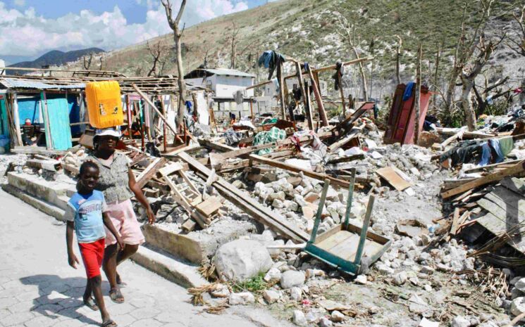 Zwie Menschen laufen entlange der Trümmer nach dem Durchzug des Hurrikan Matthew 2016 in Haiti