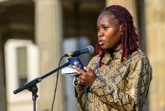 Portrait von Hilda Nakabuye bei der Rede vor dem Mikrofon