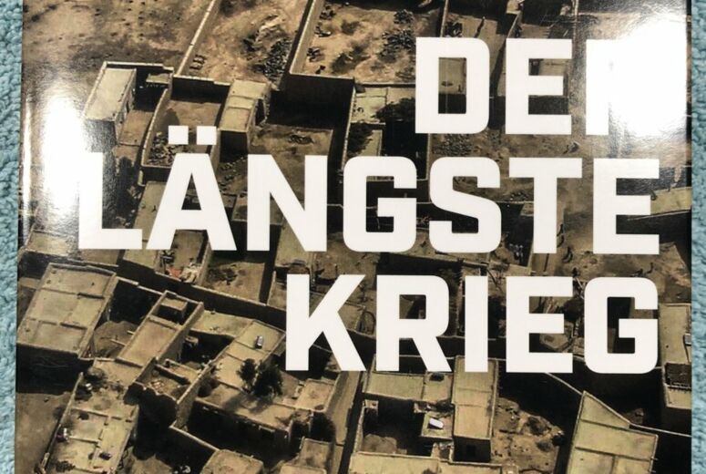 Buchcover der laengste krieg mit Vogelperspektive auf Flachdachgebaude