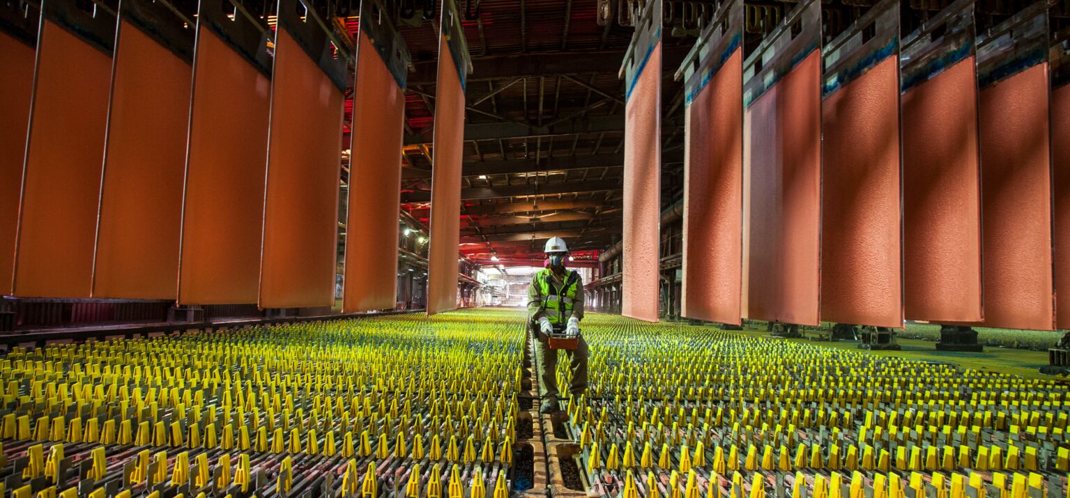 Kupferplatten in einer Produktionshalle in Chile, ein Arbeiter mit Helm und Schutzmaske in der Mitte