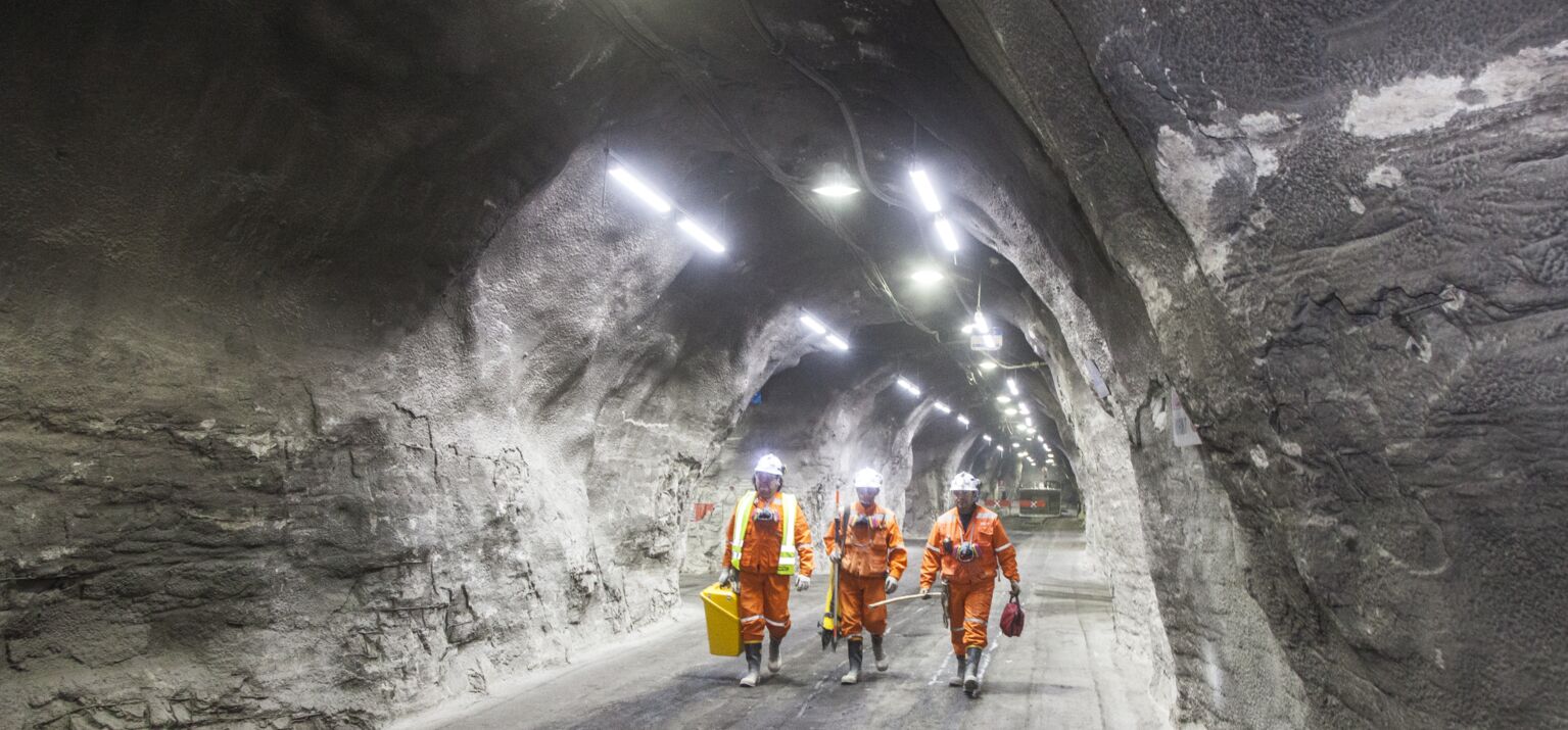 3 Bergleute in Schutzkleidung in einem beleuchteten chilenischen Kupferbergwerk