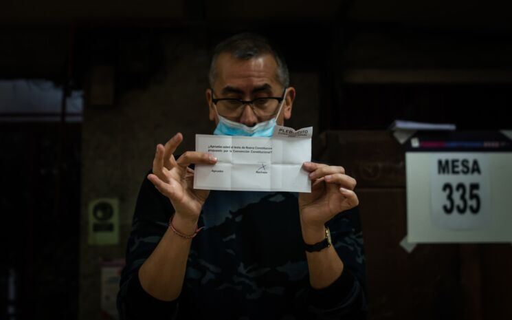 in einem Wahllokal hält eine Person einen Stimmzettel hoch, sodass alle das Ergebnis lesen können