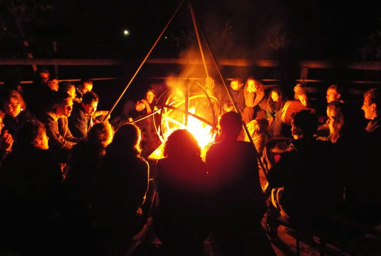 Das Bild zeigt ein Lagerfeuer mit Menschen, die für die Basisorganisierung bei Commons stehen