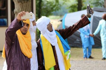 Drei Personen mit Handys beim Jahrestreffen der Tuareg-Diaspora in Frankreich