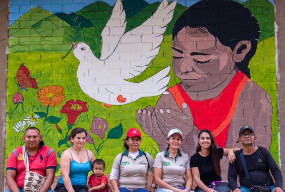 Wand Graffiti mit ehemaligen FARC-Kämpferinnen, die vor dem Wandgemälde sitzen
