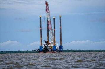 Bau des Ölterminals auf dem Meer, großer Kran und vier hohe Türme auf einer schwimmenden Plattform