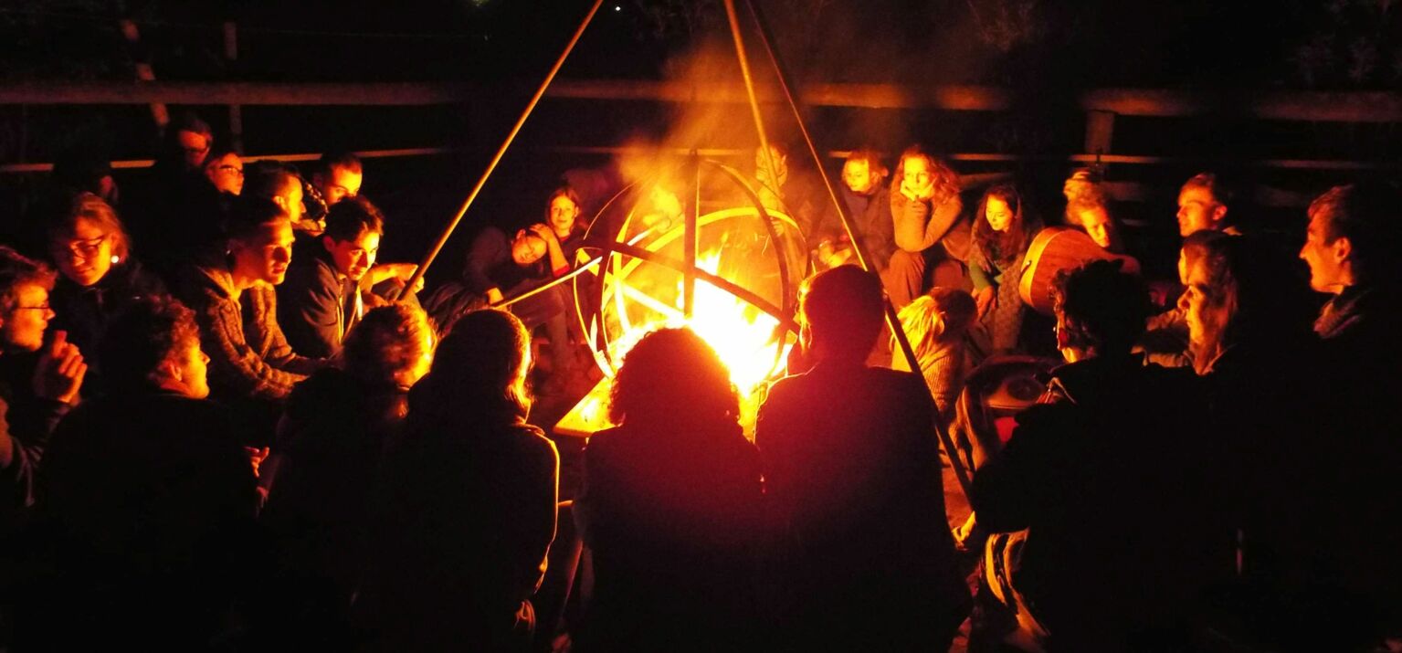 Das Bild zeigt ein Lagerfeuer mit Menschen, die für die Basisorganisierung bei Commons stehen