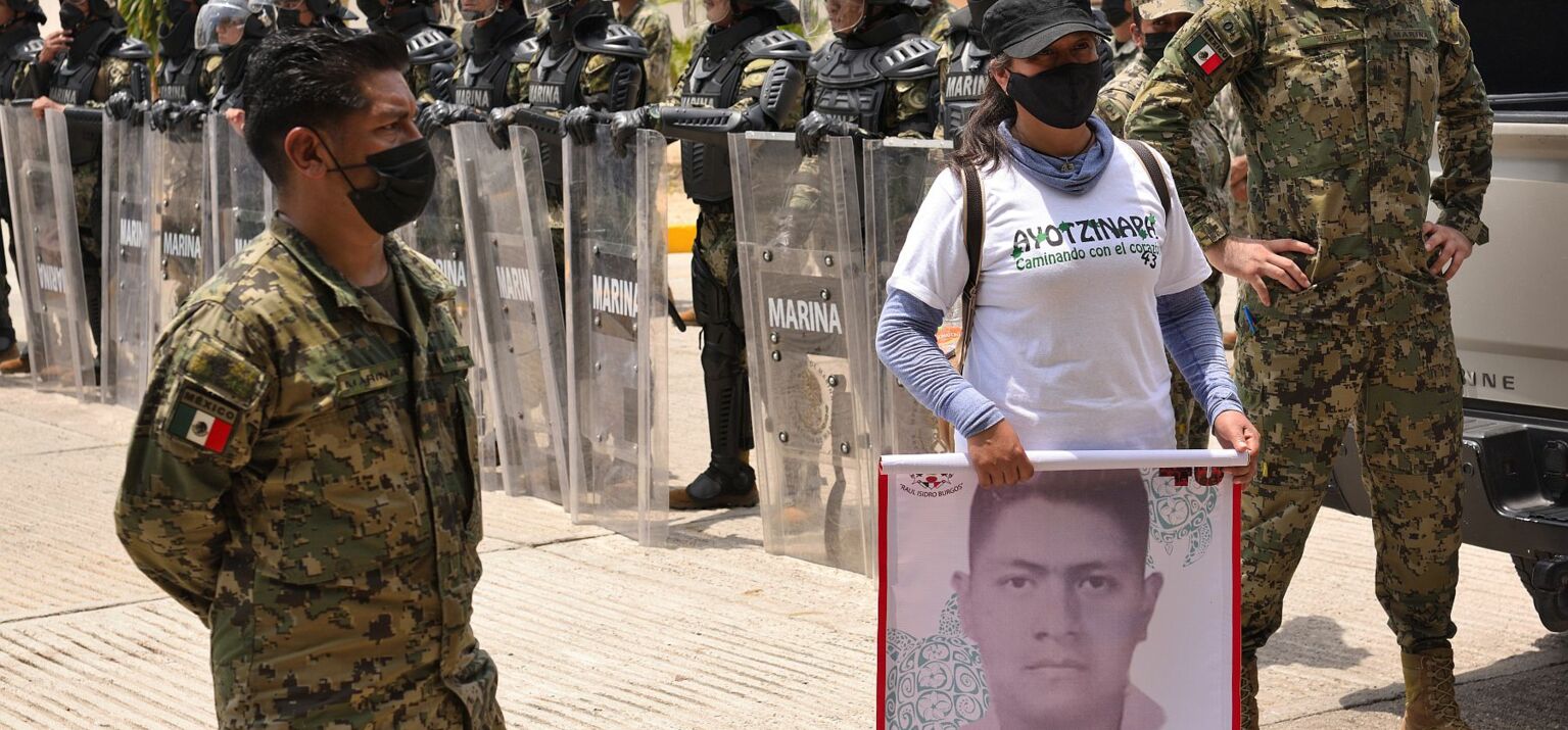 eine Studierende protestiert, umgeben von schwer geschützter Polizei und Militärs