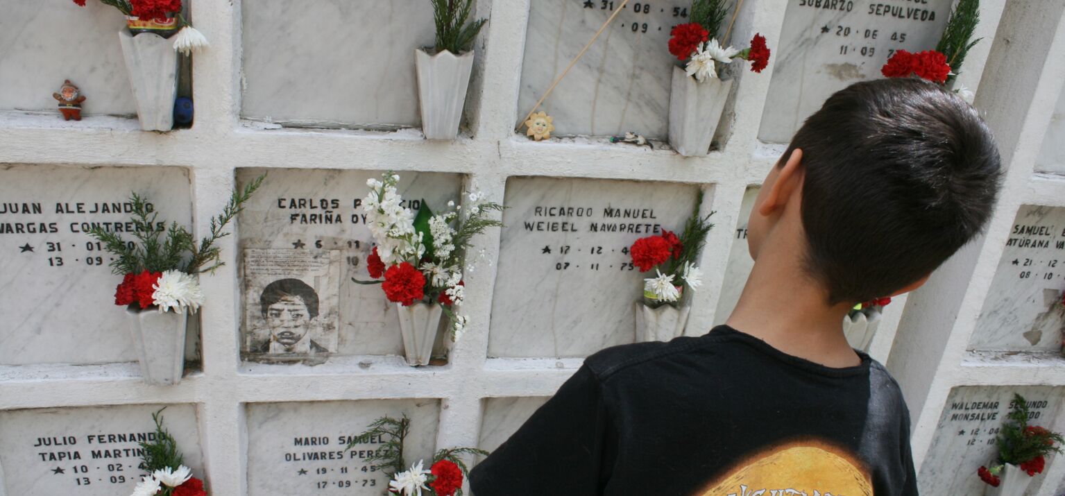 Kind schaut auf Urnengräber geschmückt mit Blumen. 50 Jahre Putsch in Chile.