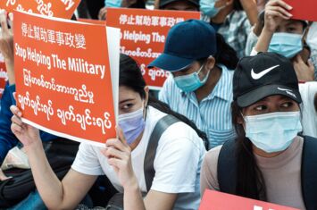 Frauen halten Protestschilder hoch mit der Aufschrift "Stop Helping the Military"