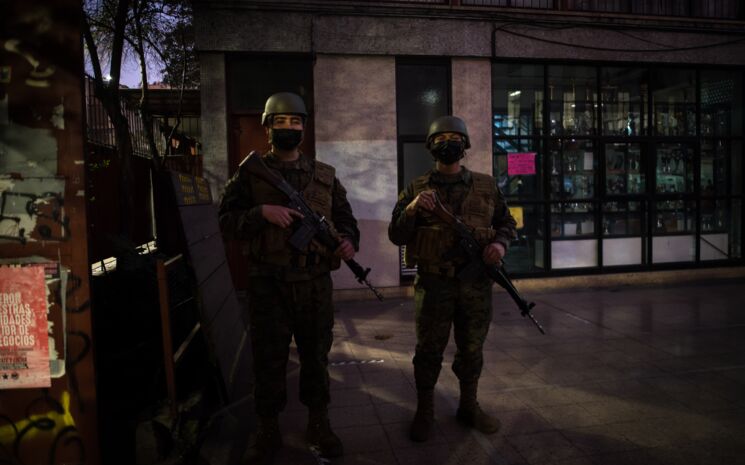 zwei Militäres mit Waffen und Schutwestevor dem Eingang eines Wahllokals im Dunkeln