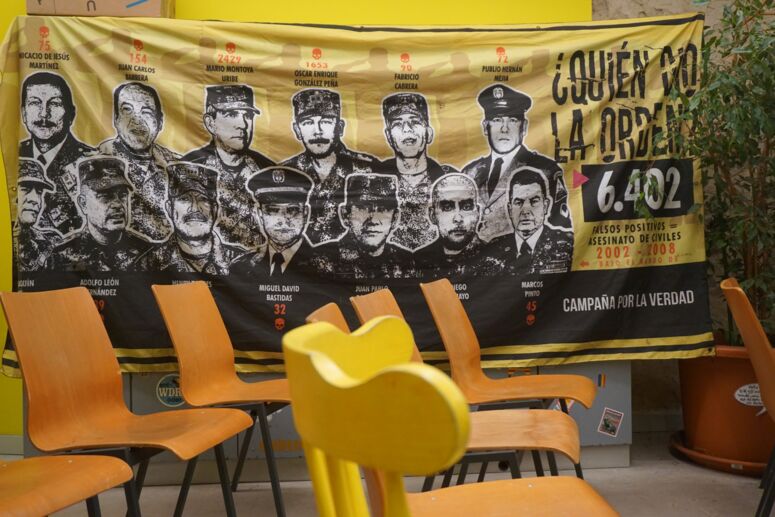 Transparent von Mafapo über die »Falsos Positivos« im Veranstaltungsraum vor leeren Stühlen