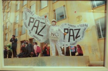 Foto einer Friedensaktivistin mit Flügeln und der Aufschrift PAZ in einer Ausstellung