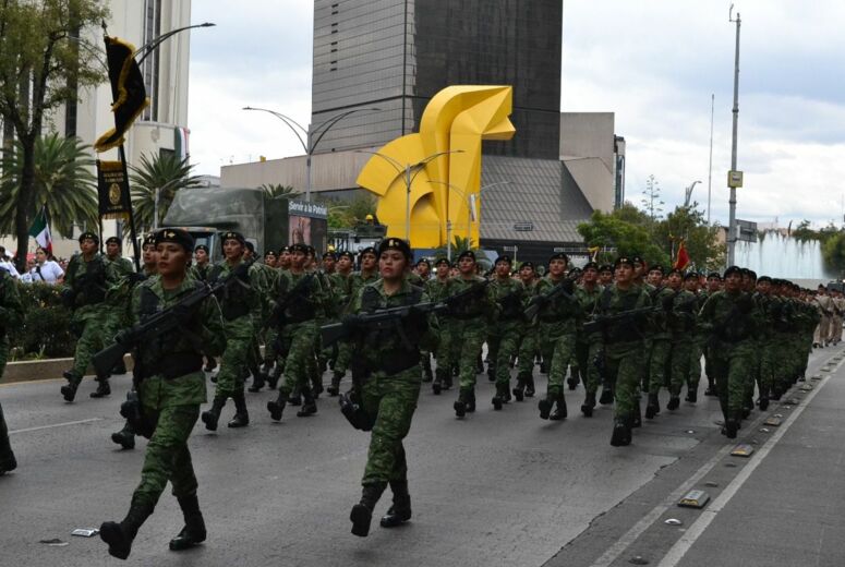 Soldatinnen marschieren in Uniform und mit Waffe in Reihen durch die Straßen von Mexiko City