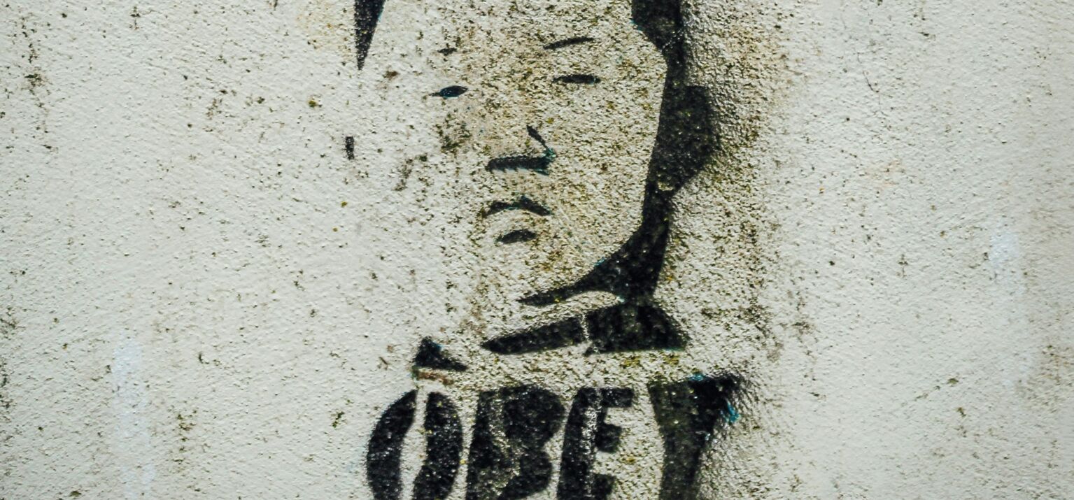 schwarzes Graffity auf heller Mauer mit der Aufschrift OBEY - steht für Autoritarismus