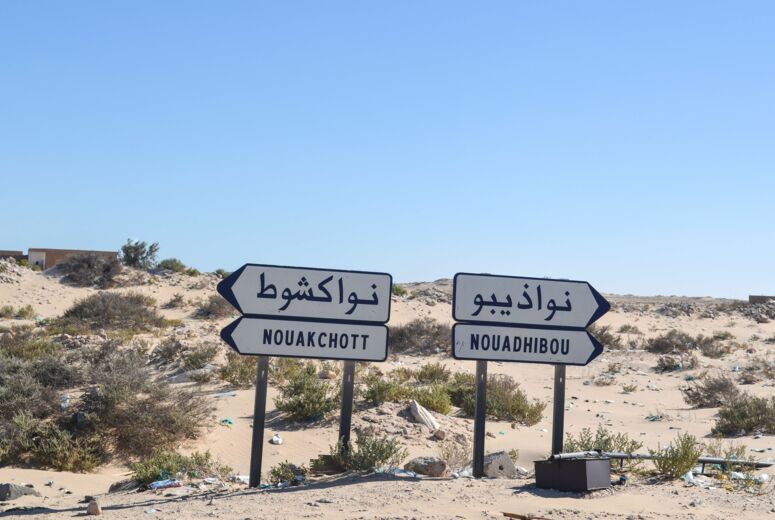 Wüstenartige Landschaft, zwei Wegweisser zeigen in verschiedener Richtungen