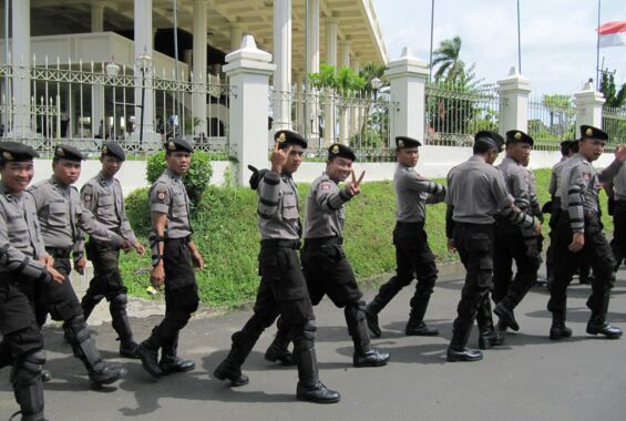 Korrupte Institution: Eine Gruppe junger indonesischer Polizeibeamten, an der Kamera vorbeilaufend.