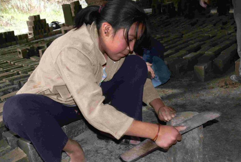 Mädchen schärft ein Messer an einem Stein. Kinderarbeit in Peru