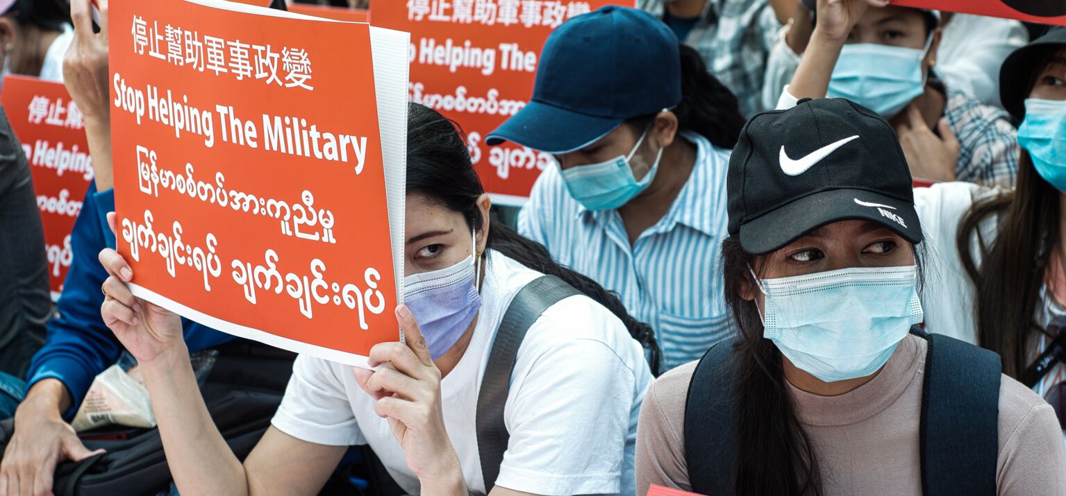 Frauen halten Protestschilder hoch mit der Aufschrift "Stop Helping the Military"