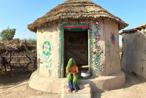 Eine Frau sitzt vor einem verzierten Lari Octa Green-Einraumhaus der Architektin Yasmeen Lari in Pakistan