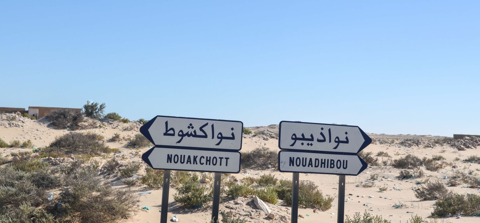 Wüstenartige Landschaft, zwei Wegweisser zeigen in verschiedener Richtungen