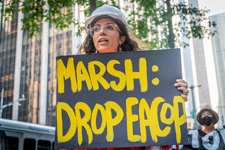 Frau mit Protestschild MARSH: Drop EACOP