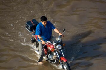 Mann fährt Motorrad durch eine überflutete Strasse in China. Die Rechte sieht Überschwemmungen im Ausland nicht als Problem.