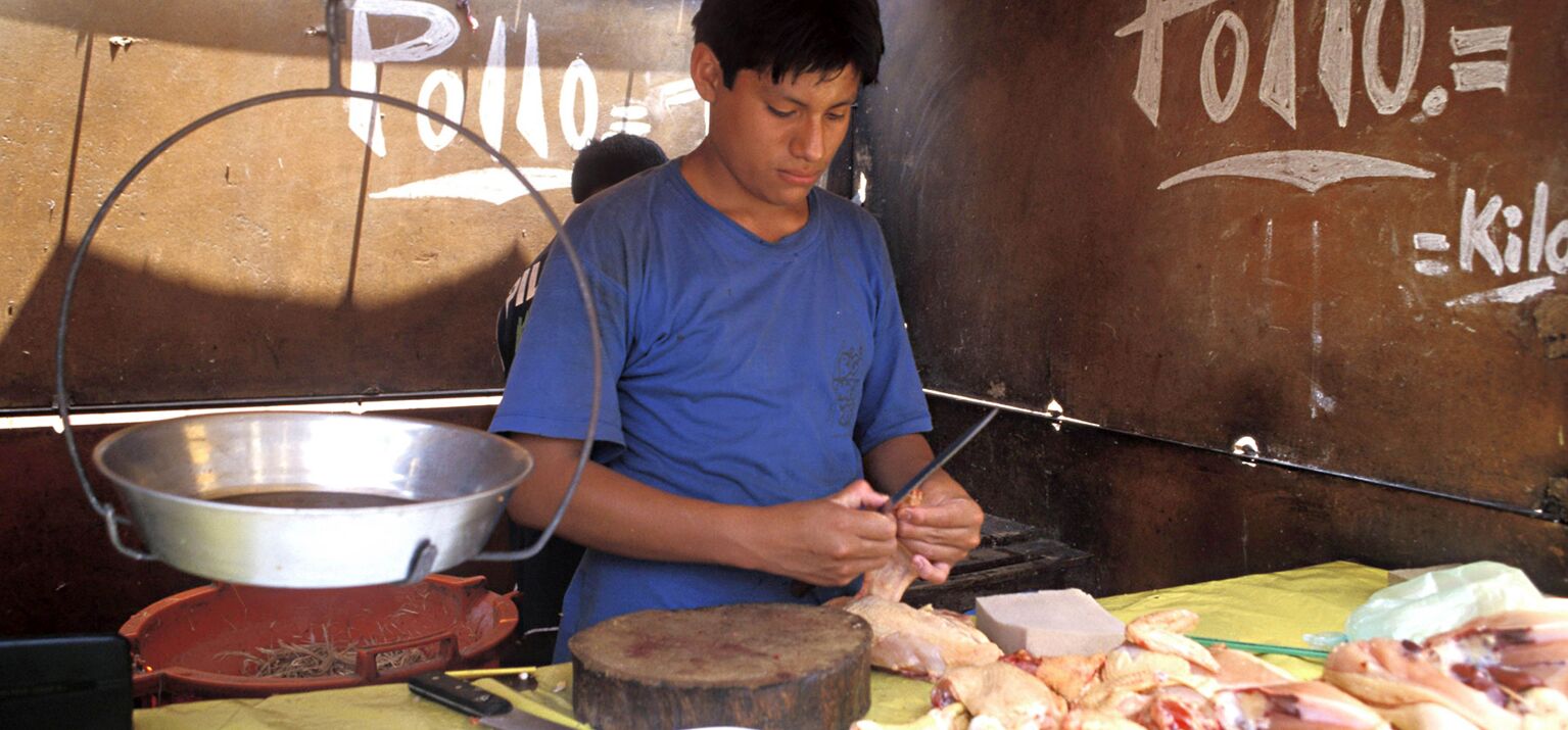 Ein Teenager in Lima, Peru, bereitet Hähnchen auf dem Markt zu