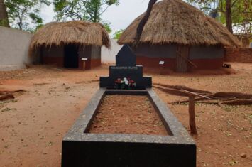 Eine Grabstätte und im Hintergrund stehen zwei Hütten